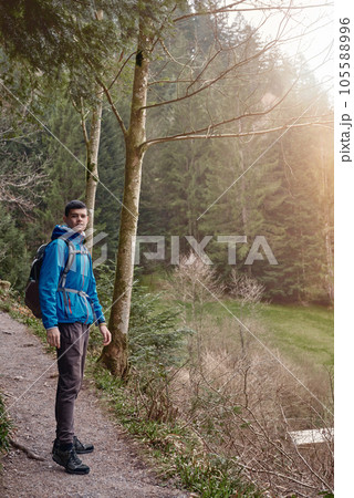 A guy tourist with a backpack stands on a mountain trail and looks into the distance. The concept of travel and adventure. Traveler Man with backpack mountaineering Travel Lifestyle concept mountains 105588996