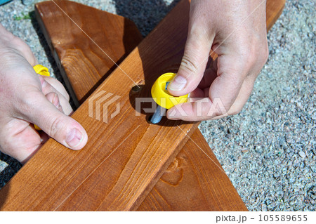 Assembly of outdoor furniture, assembler bolts two boards together. 105589655