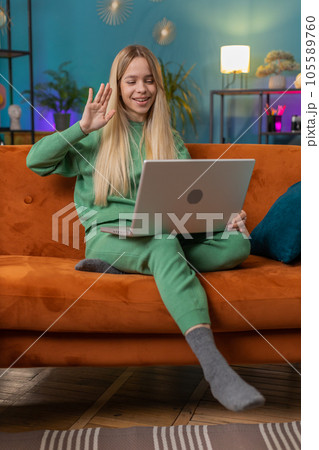 Woman sitting on home couch, looking at camera, making video conference call with friends or family Woman sitting on home couch, looking at camera, making video conference call with friends or family 105589760