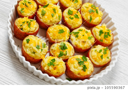 baked stuffed red potato on white baking dish 105590367