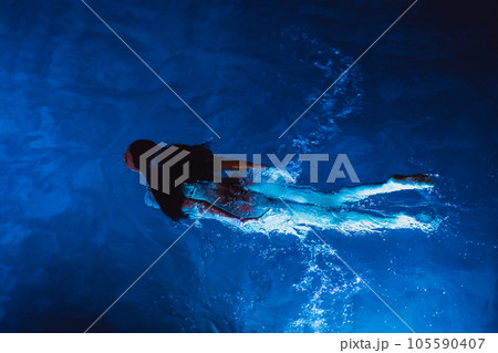Swimmer woman in swimming pool at night on vacations, view from above Swimmer woman in swimming pool at night on vacations, view from above 105590407