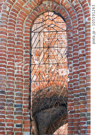 Stained glass window of an old brick church. Historic medieval architecture Stained glass window of an old brick church. Historic medieval architecture 105591263