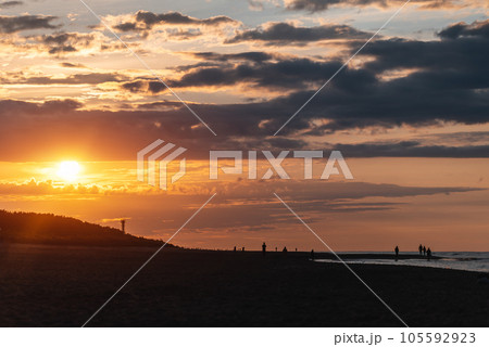 beautiful sunset over sea and beach with dramatic clouds and orange sun light 105592923