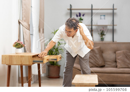 Asian older man finding something that he forgot it in drawers.. 105599708