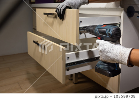 Worker fix over tight drawer slides in kitchen. Concept Fix stuck wooden drawer slides. 105599709