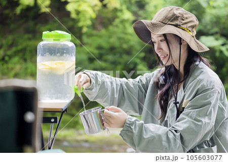 ドリンクサーバーからレモン水を注ぐ若い女性 アウトドアイメージ ドリンクサーバーからレモン水を注ぐ若い女性 アウトドアイメージ 105603077