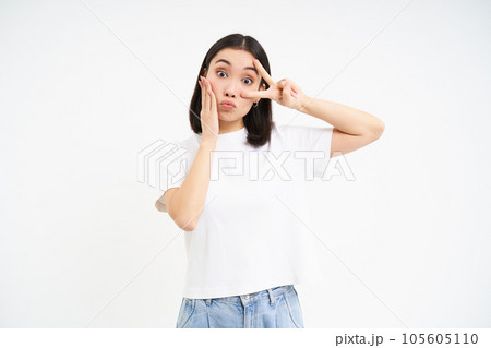 Positive korean girl, shows peace, v-sign and kissing face, posing cute against white background 105605110