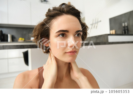 Fitness girl in activewear, doing yoga at home, stretching and working out, massaging her neck with pleased, relaxed face expression 105605353