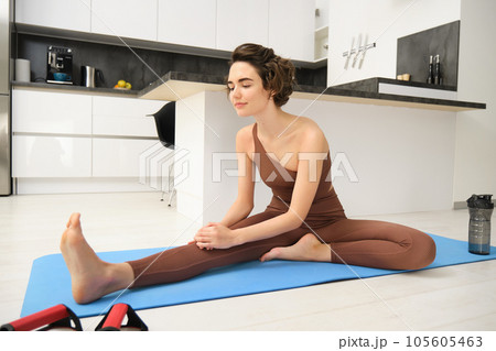 Image of brunette girl, stretching her legs, doing fitness workout, feet exercises to warm up before yoga, training at home alone 105605463