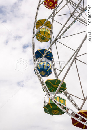 Big Ferris wheel against the sky on a cloudy day. Cabins in different colors. Place of entertainment and recreation.ferris wheel against a blue sky. High quality photo 105605546