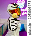 Girl in a motorcycle, multi-colored, closed helmet and white overalls, with a lollipop in her hand, posing on a purple background 105606473