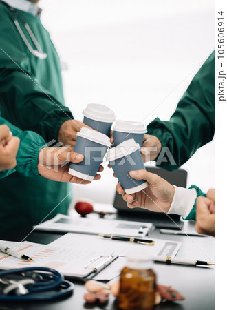 Medical team,  holds a cup of coffee and smiles happily. working together as a team at the hospital.. 105606914