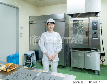 調理室の中に立つ調理服を着た若い女性 105609499