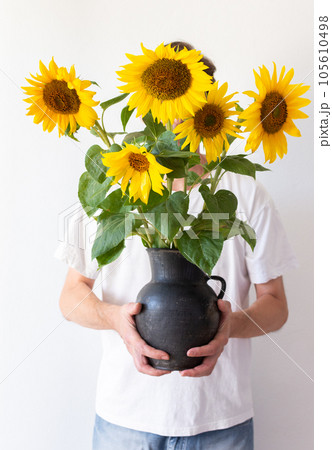 A man holds a jug with sunflowers 105610498