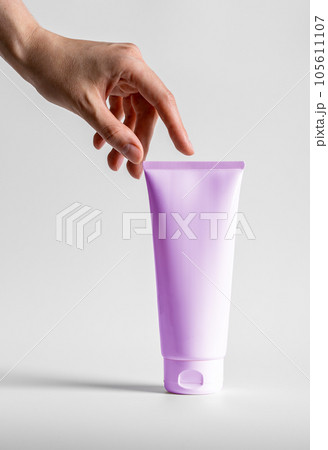 Hand touching big cream tube, cosmetic product mock up, blank package for beauty body moisturizer gel, mask 105611107