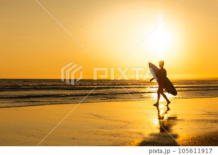 Silhouette of a man walking to the ocean at bright late sunset 105611917