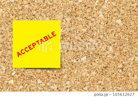 Yellow note paper with word acceptable on cork board background with copy space 105612627