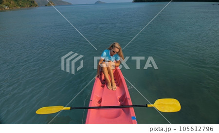Pretty slim woman in elegant swimsuit lies in pink plastic kayak drifting on azure ocean at exotic resort upper view. Pretty slim woman in elegant swimsuit lies in pink plastic kayak drifting on azure ocean at exotic resort upper view. 105612796