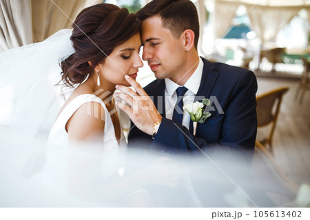 Young bride and groom in a cafe. Husband and wife hold each other's hands. Loving couple in a restaurant. Young bride and groom in a cafe. Husband and wife hold each other's hands. Loving couple in a restaurant. 105613402