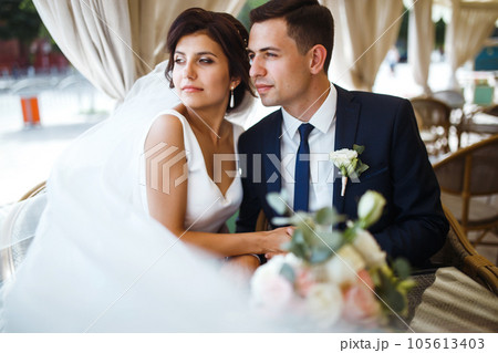 Young bride and groom in a cafe. Husband and wife hold each other's hands. Loving couple in a restaurant. Young bride and groom in a cafe. Husband and wife hold each other's hands. Loving couple in a restaurant. 105613403