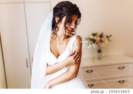 Morning of the bride. Beautiful smiling brunette bride in a white dress with a wedding bouquet in her hands. Morning of the bride. Beautiful smiling brunette bride in a white dress with a wedding bouquet in her hands. 105613603