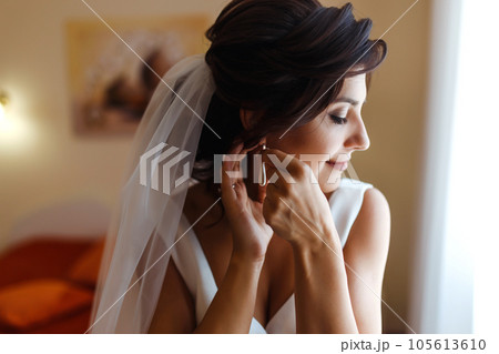 Morning of the bride. Beautiful smiling brunette bride in a white dress with a wedding bouquet in her hands. Morning of the bride. Beautiful smiling brunette bride in a white dress with a wedding bouquet in her hands. 105613610
