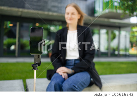 Female teen vlogger recording video using smartphone on tripod 105616242