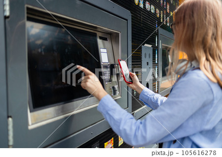 Woman client using automated self service post terminal machine or locker. Mail shipping concept 105616278