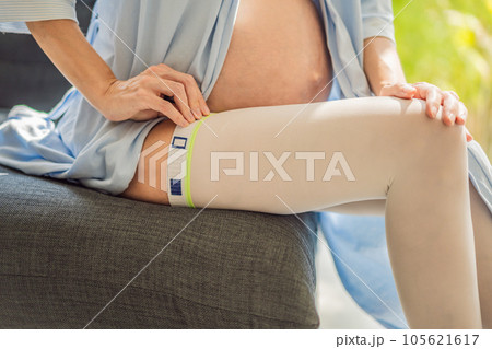 A content and comfortable pregnant woman wearing compression stockings, ensuring better leg health and support during her pregnancy journey A content and comfortable pregnant woman wearing compression stockings, ensuring better leg health and support during her pregnancy journey 105621617