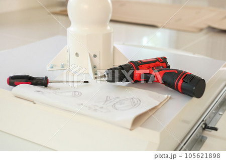 Cordless screwdriver on wood table assembly furniture concept Cordless screwdriver on wood table assembly furniture concept 105621898
