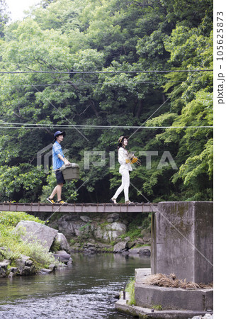 荷物を持ってキャンプ場に向かうカップル 荷物を持ってキャンプ場に向かうカップル 105625873