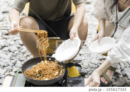 屋外で作った焼きそばを取り分ける男女 アウトドアイメージ 屋外で作った焼きそばを取り分ける男女 アウトドアイメージ 105627385