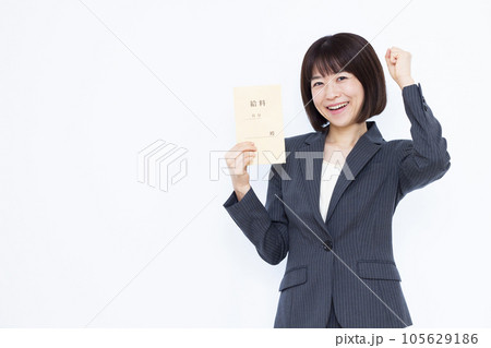 白い背景の前で給料袋を持ちガッツポーズをしている30代の女性 105629186