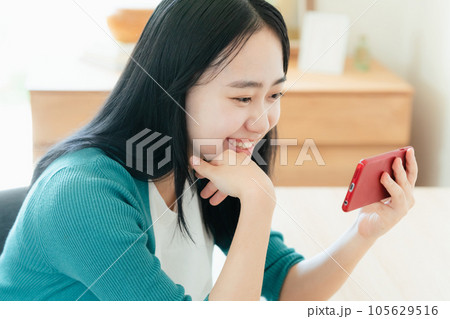 スマートフォンで動画視聴する若い女性 スマートフォンで動画視聴する若い女性 105629516