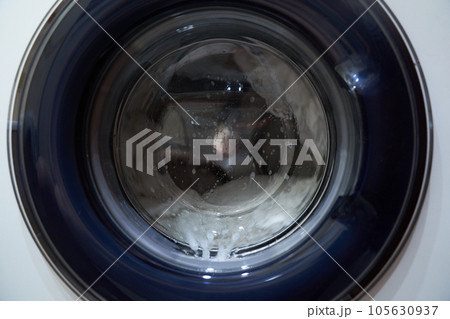 Clothes are washed in the washing machine. The drum of the washing machine rotates. Housework of a housewife. Laundry. High quality photo Clothes are washed in the washing machine. The drum of the washing machine rotates. Housework of a housewife. Laundry. High quality photo 105630937