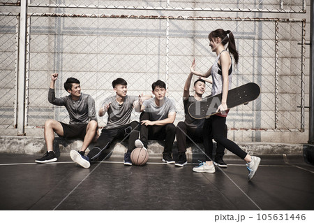 young asian adult woman skateboarder giving a group of young men hi-five 105631446