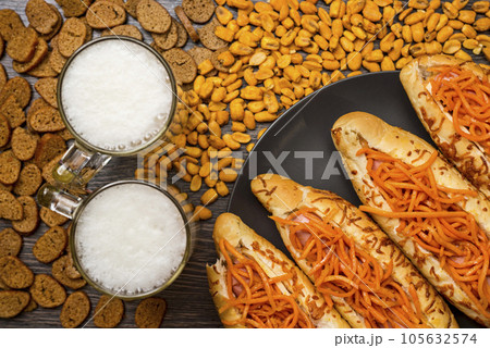Photo of two glasses of beer with hot dogs, crackers, corn and peanuts. Photo of two glasses of beer with hot dogs, crackers, corn and peanuts. 105632574