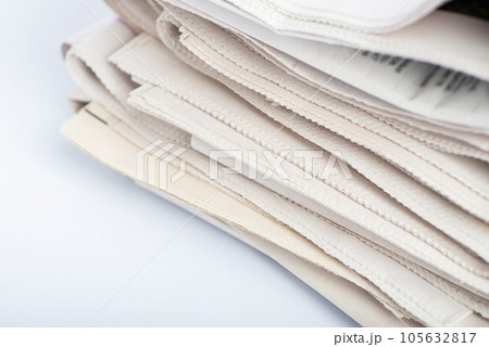 A pile of newspapers on a light background, top view.  105632817