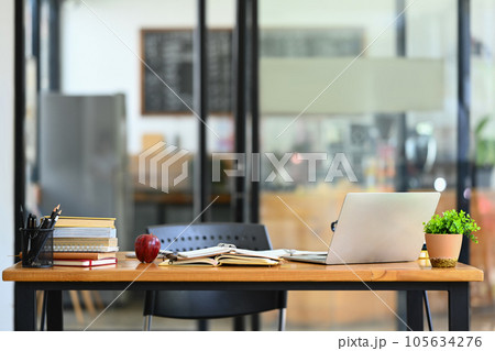 Laptop, books, potted plant and with office supplies on wooden table. 105634276