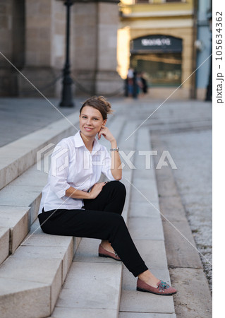 Portrait of lady in formal outfit sits on stairs. Woman spent time after work Portrait of lady in formal outfit sits on stairs. Woman spent time after work 105634362