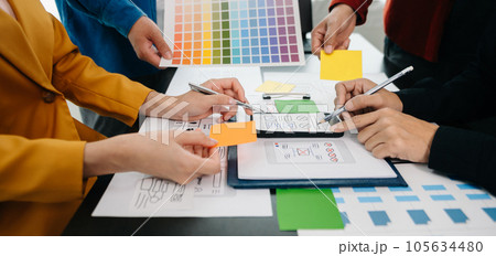 UX developer and ui designer brainstorming about mobile app interface wireframe design with customer breif and color code at office.. UX developer and ui designer brainstorming about mobile app interface wireframe design with customer breif and color code at office.. 105634480