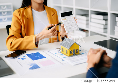 Real estate broker agent presenting and consult to customer to decision making sign insurance form agreement, home model, concerning mortgage loan offer in office 105635044