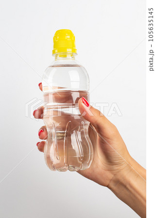 Transparent plastic bottle with fresh water in a female hand on a white background. 105635145