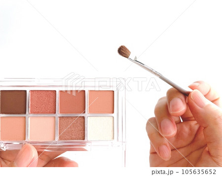 アイシャドウパレットとメイクブラシを持つ女性の手元 105635652