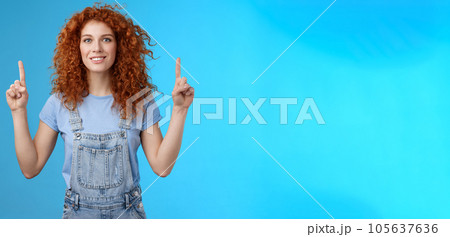 Motivated happy cheerful redhead silly curly woman pointing up inrdex finger smiling charmed impressed excited showing awesome promo discuss interesting advertisement blue background 105637636