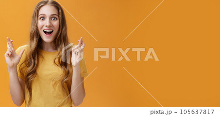Waist-up shot of interested amused and enthusiastic good-looking woman in casual t-shirt crossing fingers for good luck smiling amazed and delighted being happy and hopeful things will be well 105637817