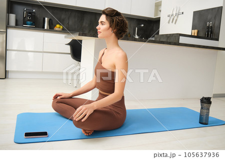 Fit healthy young woman doing pilates yoga exercise fitness training workout at home interior standing in warrior pose. Physical activity for body and mind relaxation, healthy lifestyle concept 105637936