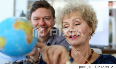 Portrait of aged mother pointing at coloured globe and smiling Portrait of aged mother pointing at coloured globe and smiling 105639912