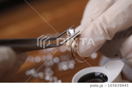 Close-up of goldsmith hand decorating precious ring with beautiful diamonds 105639945