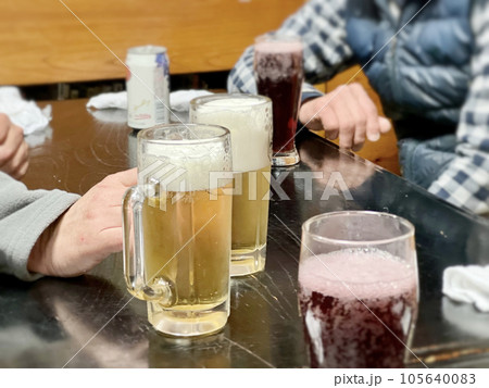 ビールジョッキとジュースと缶飲料の置かれたテーブルと人物 ビールジョッキとジュースと缶飲料の置かれたテーブルと人物 105640083